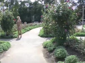 Голая Миранда наслаждается ароматов цветущих роз в парке